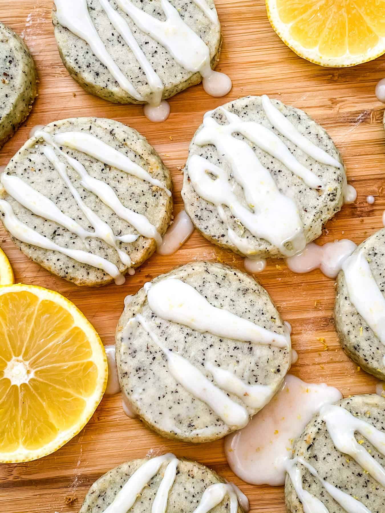 Earl Grey Shortbread Cookies spread out on a cutting board with drizzled glaze and lemon slices