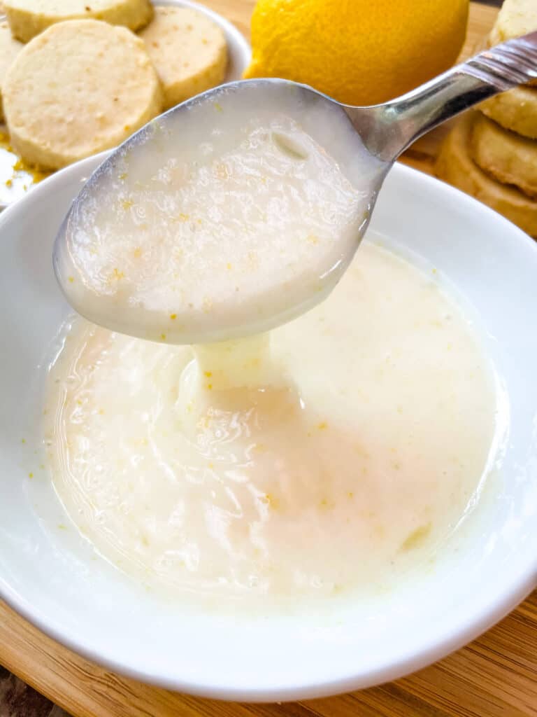 A spoon overflowing with Lemon Glaze into a bowl