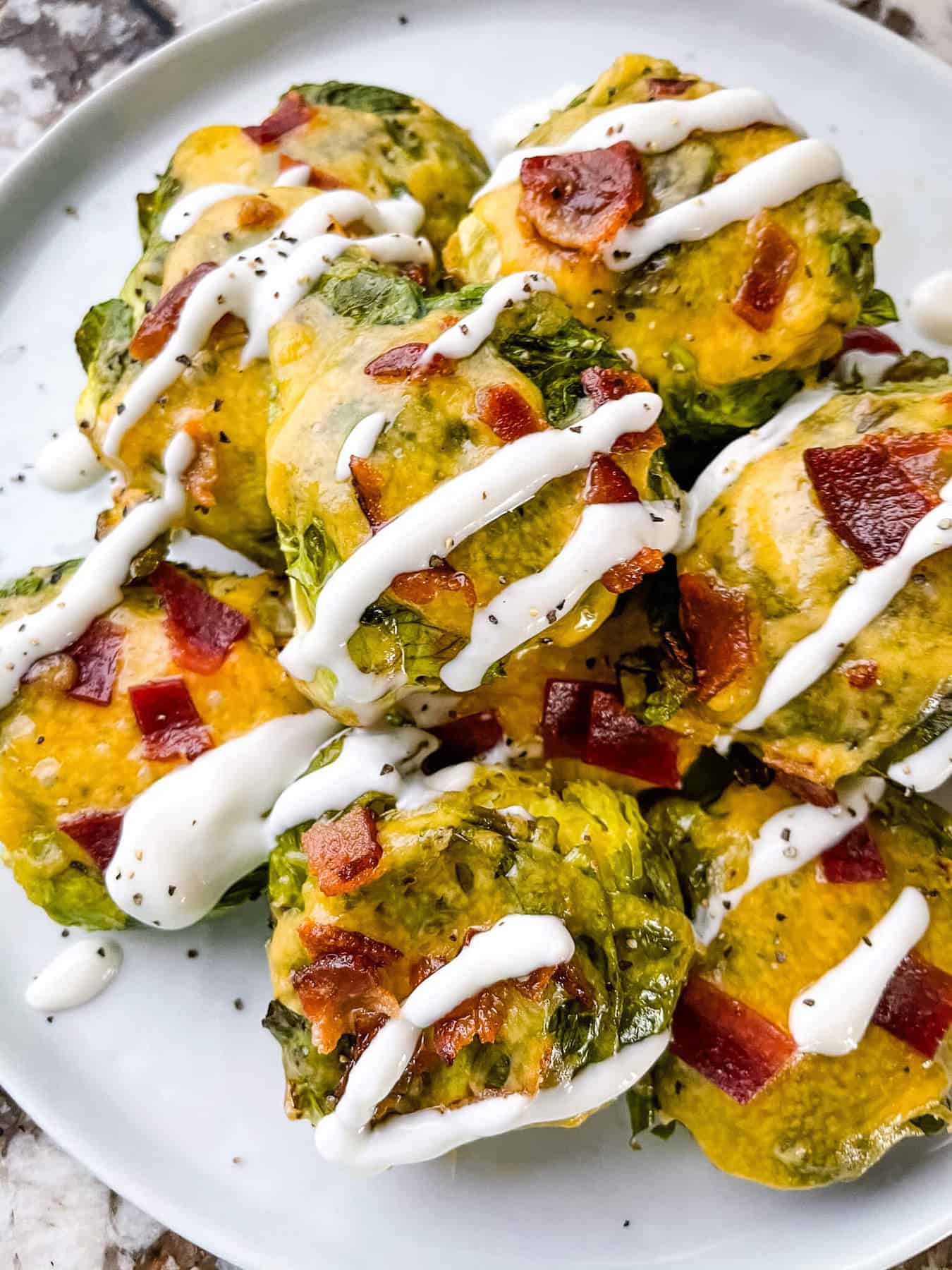 A pile of Loaded Smashed Brussels Sprouts drizzled with sour cream