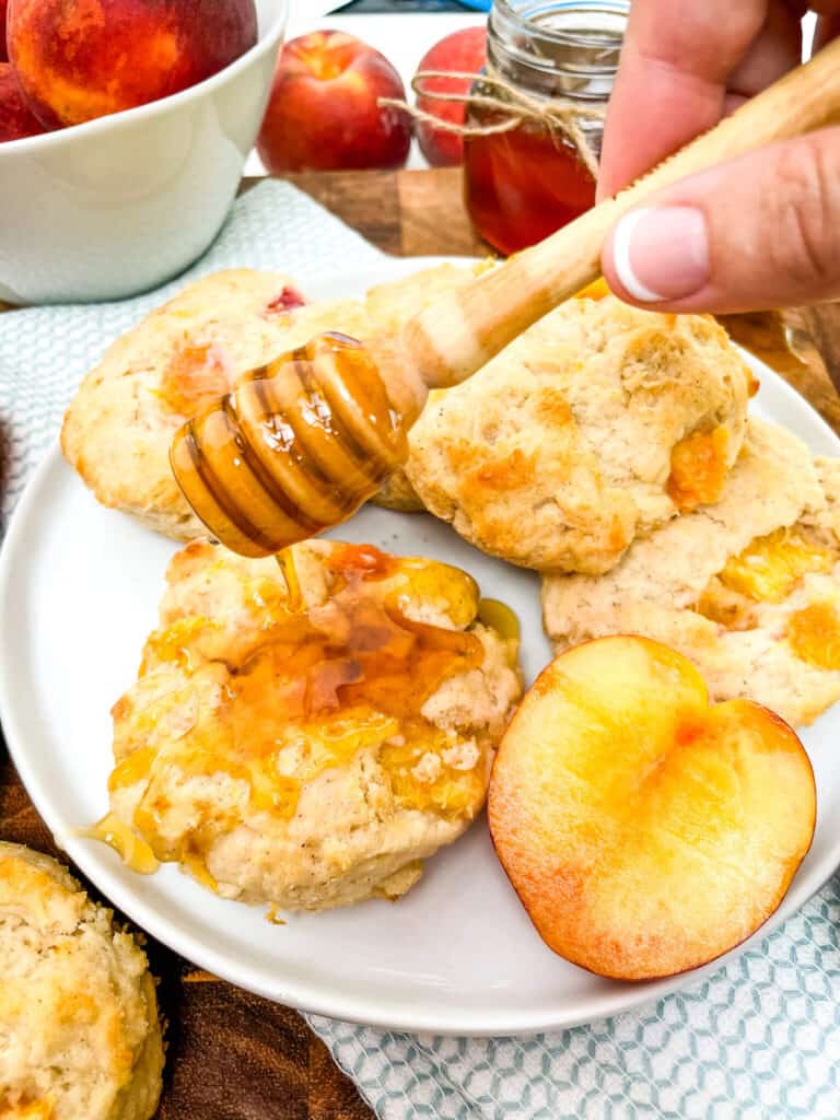 A hand drizzling honey on a scone