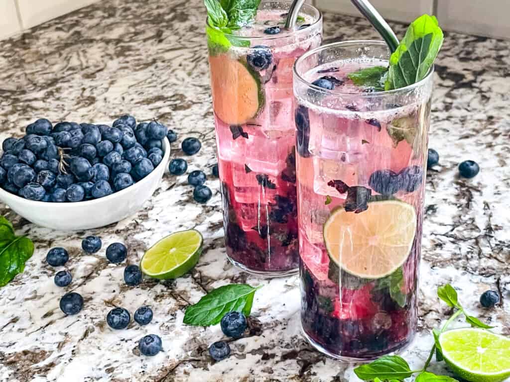 Two Blueberry Mojitos with berries around them