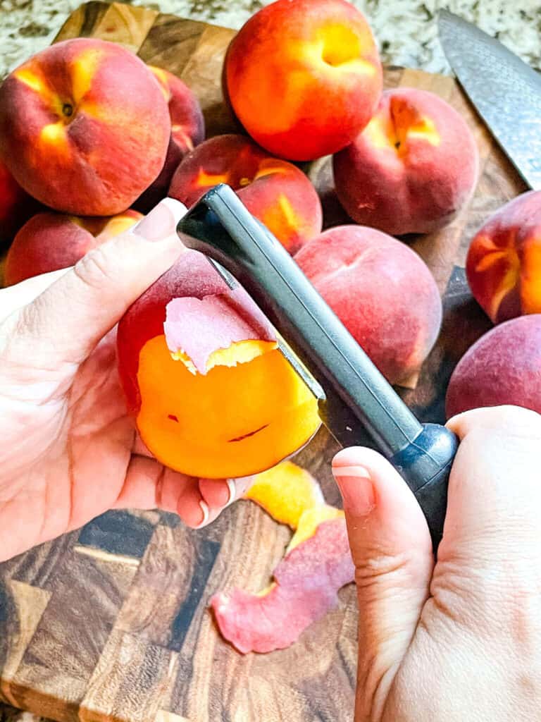 A hand using a peeler on the fruit