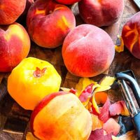 A pile of peaches with one partially peeled