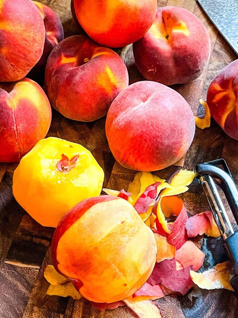 A pile of peaches with one partially peeled