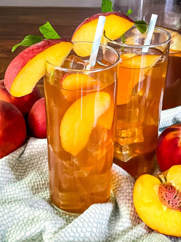 Two tall glasses of the drink with pieces of fruit in it