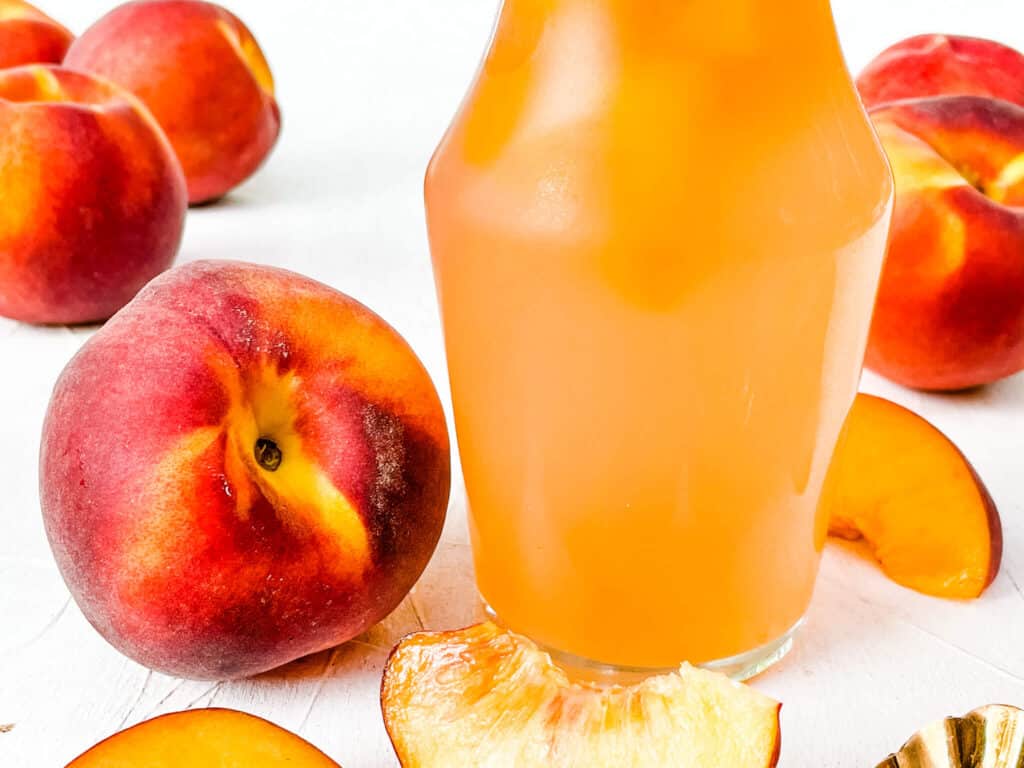 Peach Syrup close up in the jar with peaches around it