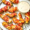 A white plate filled with Smoked Jalapeno Poppers and dipping sauce