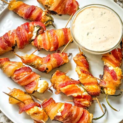 A white plate filled with Smoked Jalapeno Poppers and dipping sauce