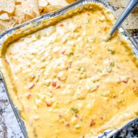 A foil pan full of melted Smoked Queso with chips