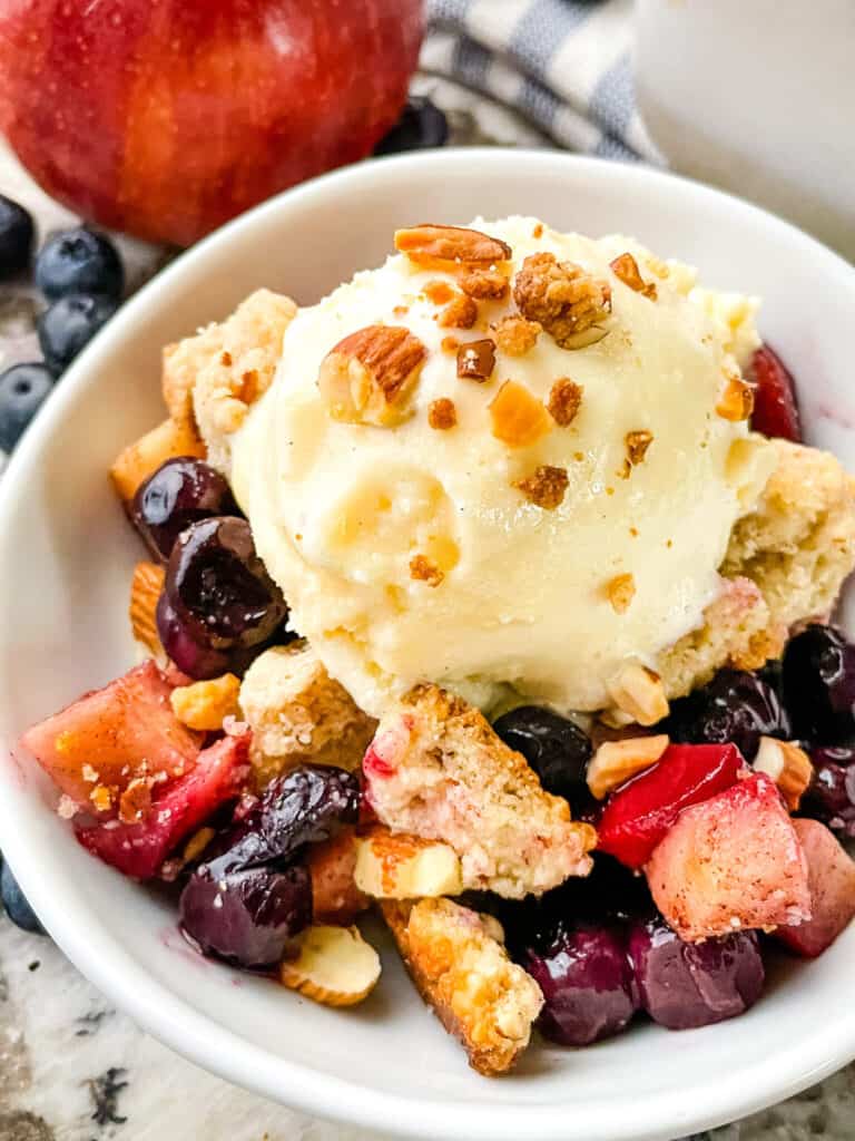 A small white bowl with some crumble and ice cream