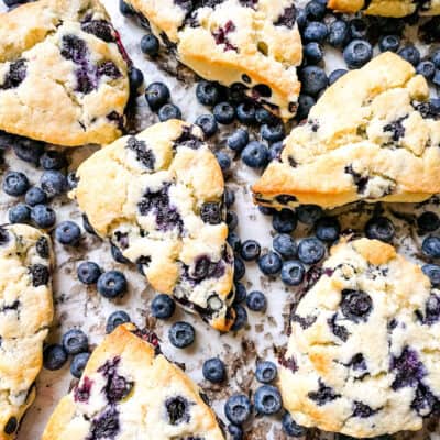 Blueberries Scones scattered on a counter surrounded by blueberries