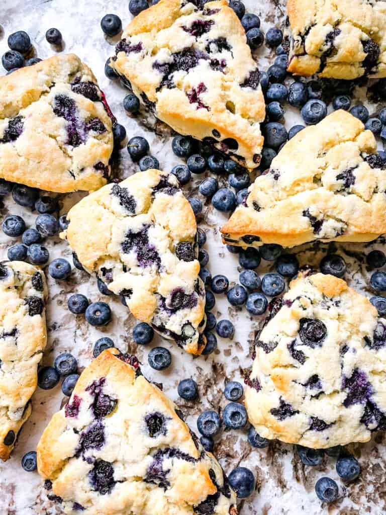 Blueberries Scones scattered on a counter surrounded by blueberries
