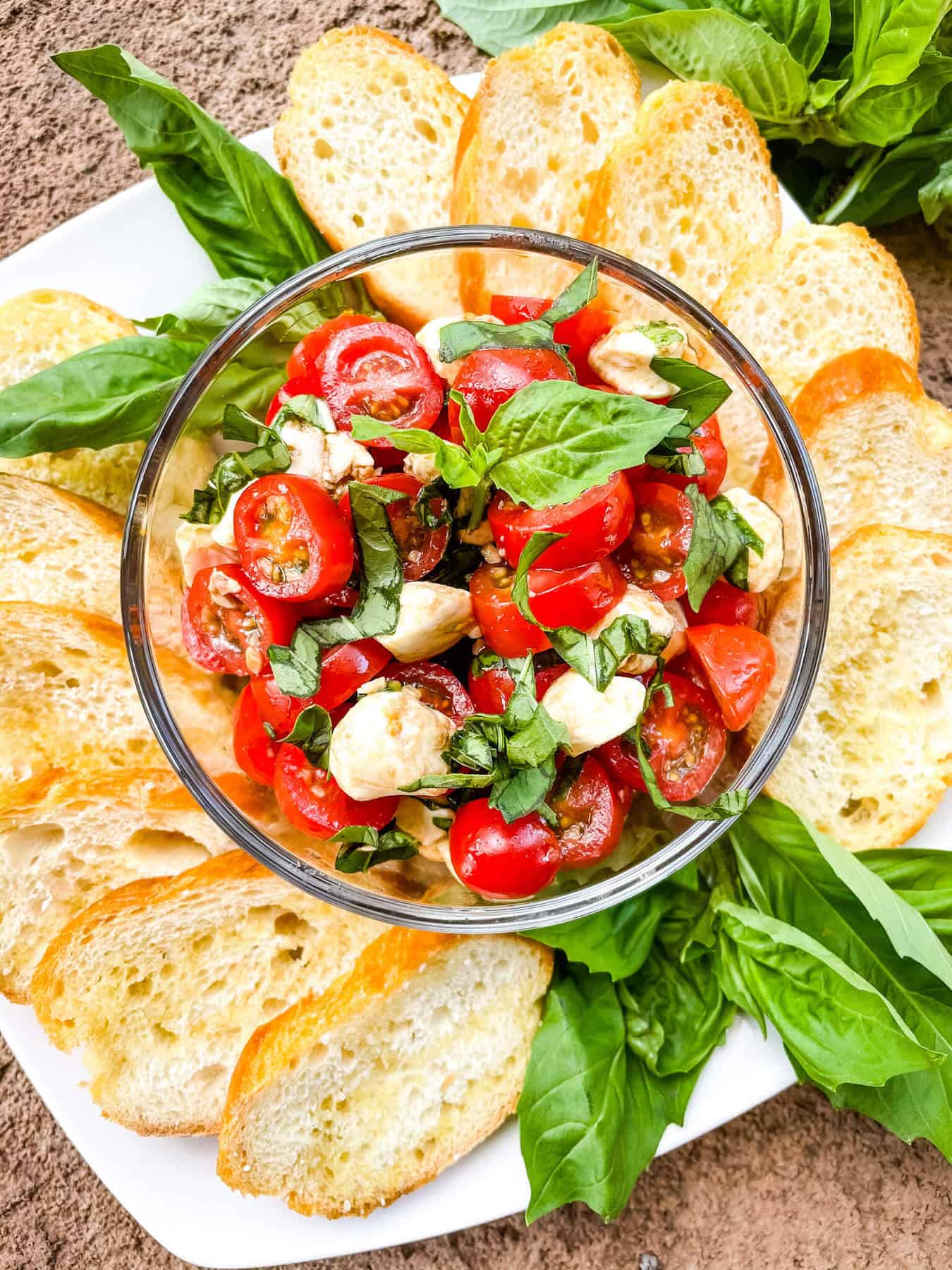 A bowl of the topping with bread and basil around it on a plate