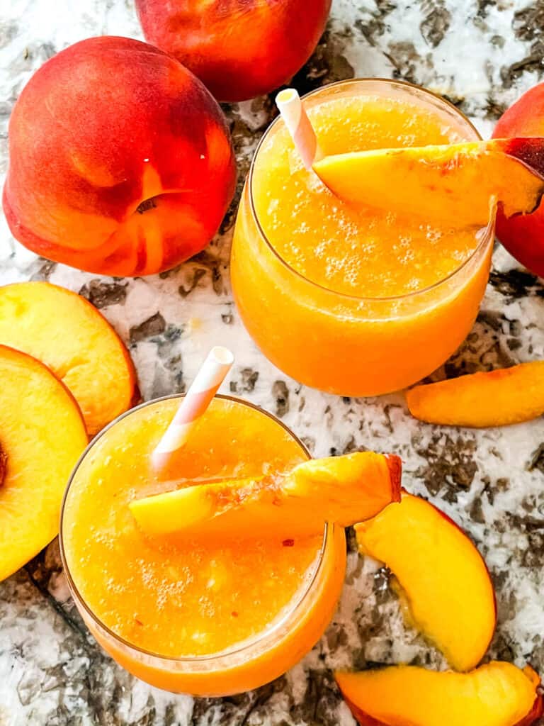 Two peach drinks from the top with peaches around them