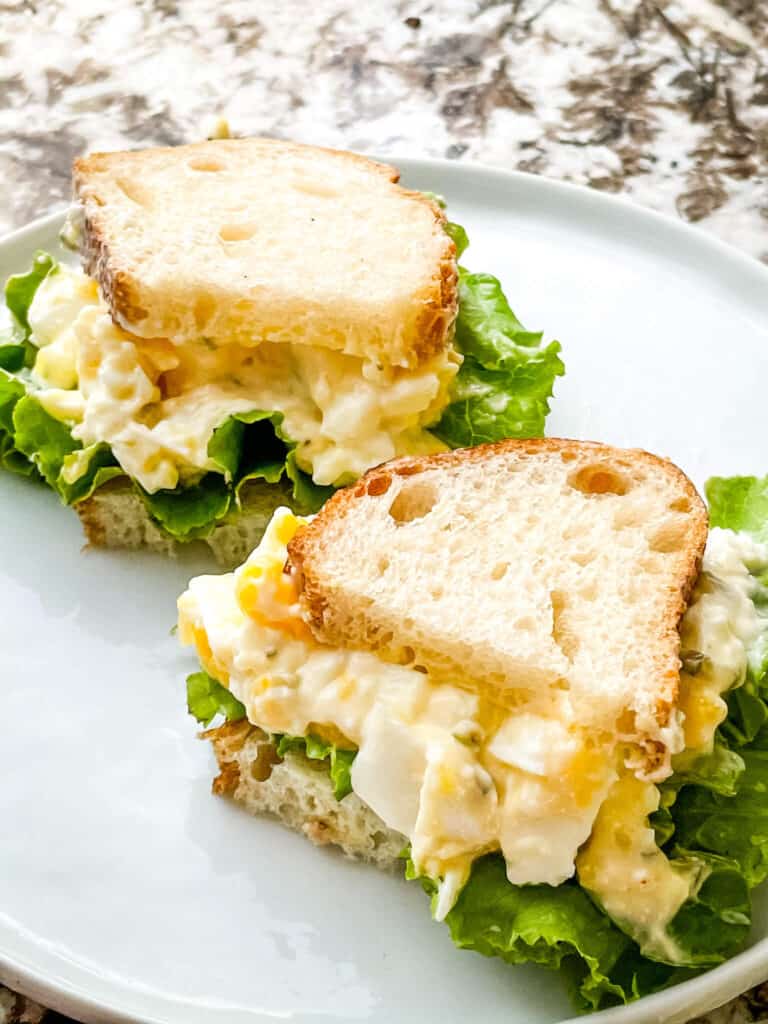 Two halves of the Egg Salad Sandwich on a white plate