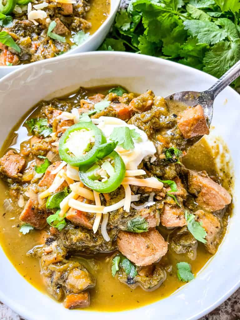 A spoon digging into a serving of Hatch Pork Green Chili