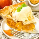 Slice of Peach pie with ice cream and a fork