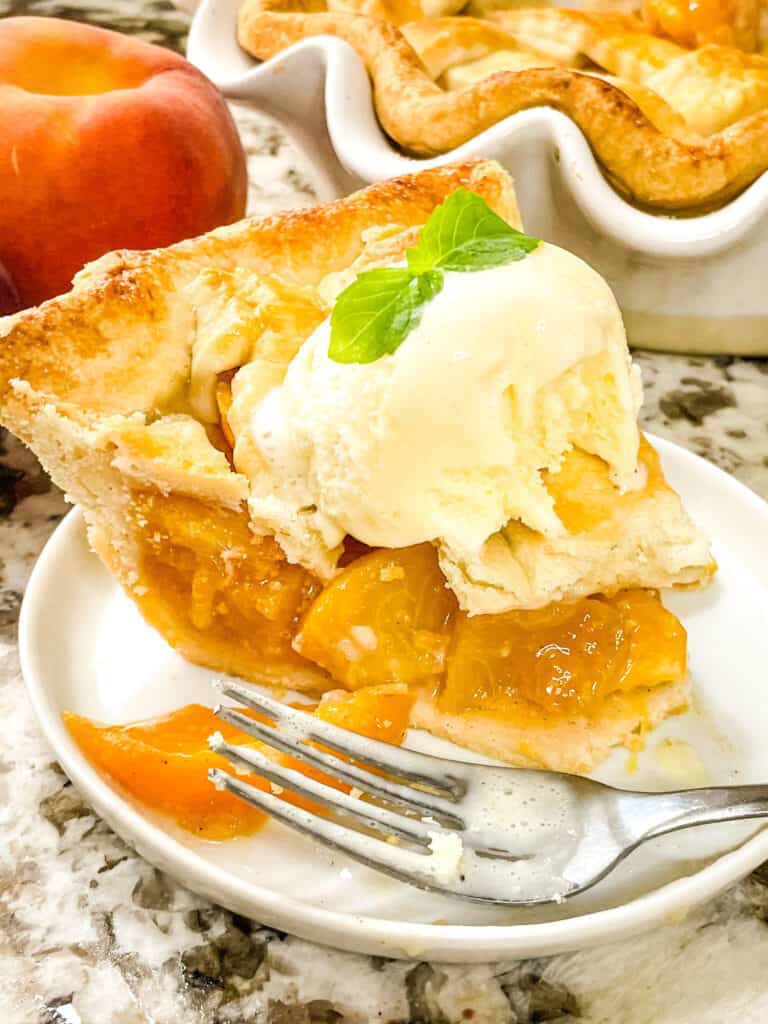 Slice of Peach pie with ice cream and a fork