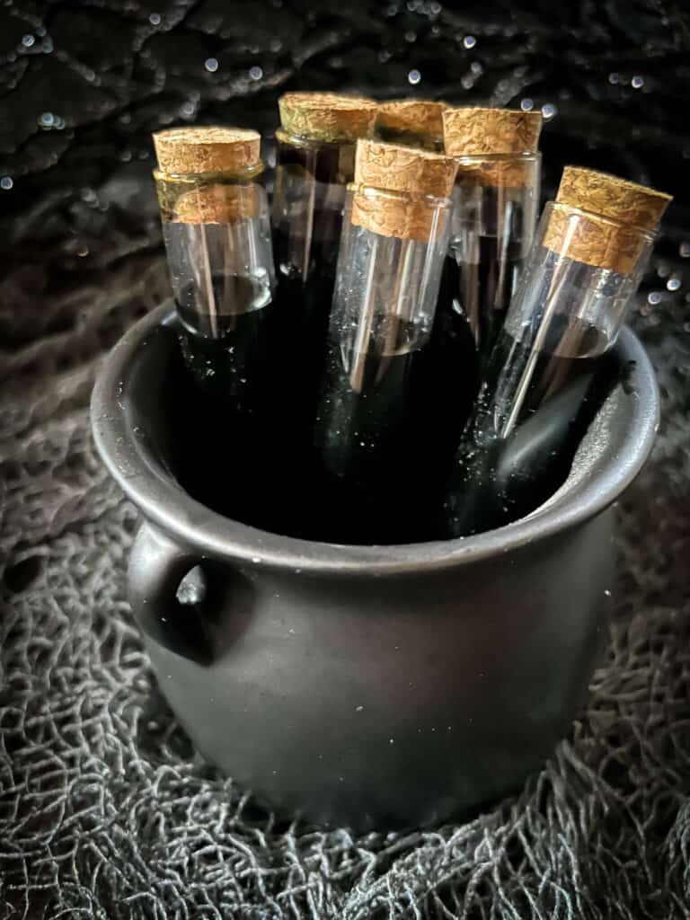 A small black cauldron filled with the poison vials
