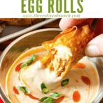 Pin image of a hand dunking a Buffalo Chicken Egg Roll with title at top