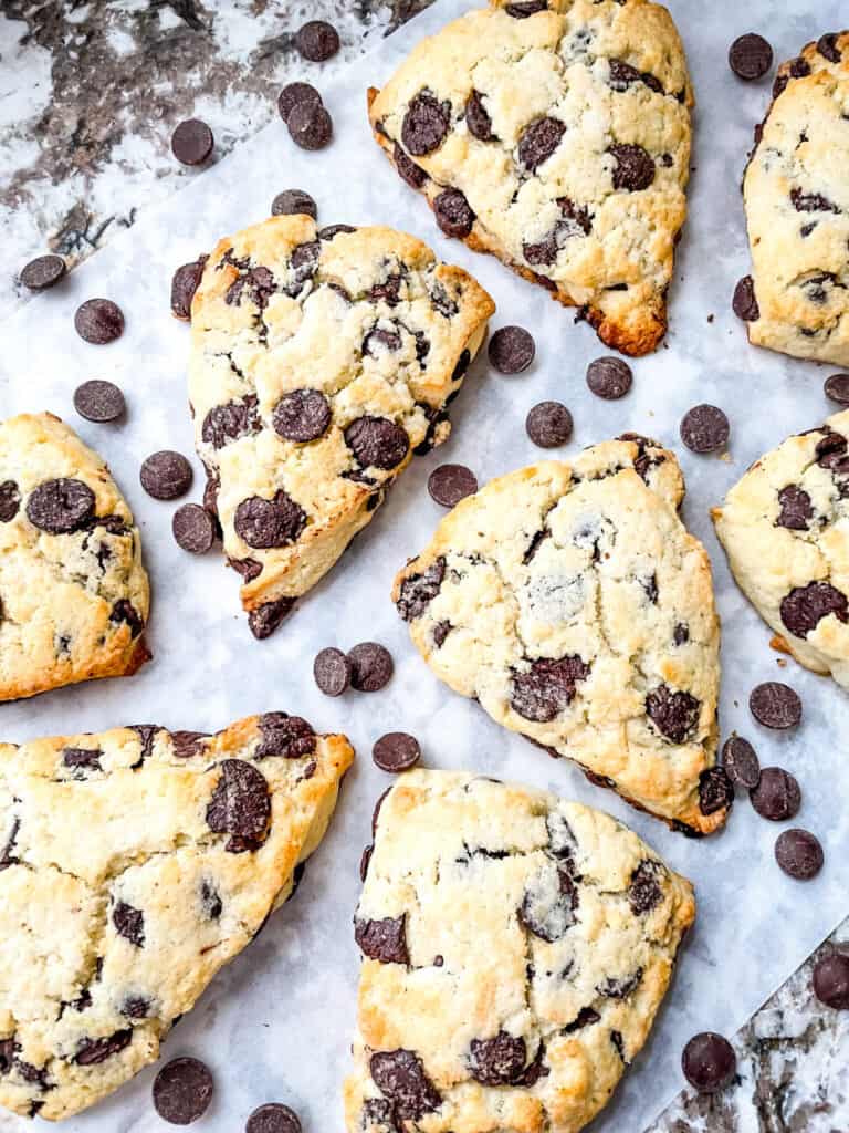 Chocolate Chip Scones scattered on parchment paper with chocolate chips