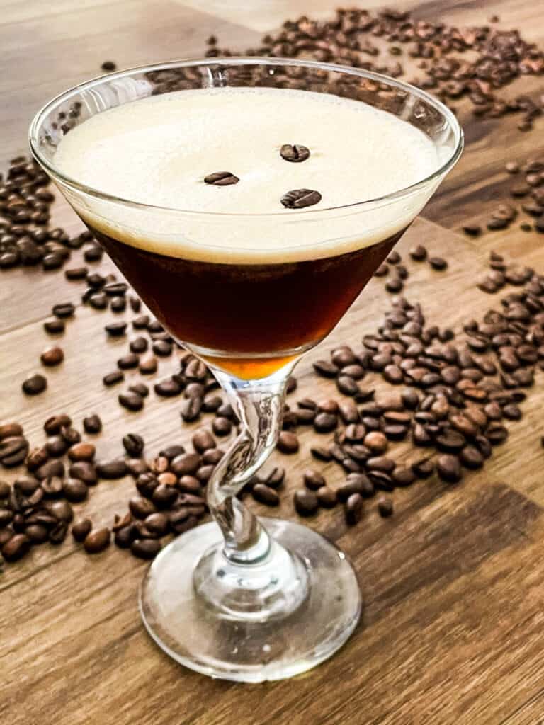 An Espresso Martini in a glass with coffee beans around it