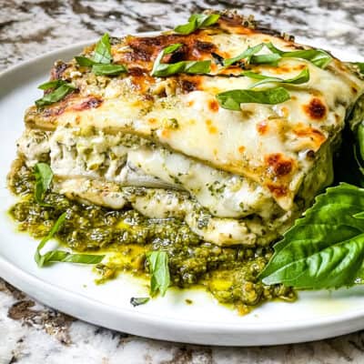 Side view of Lasagna al Pesto on a plate with dresh basil