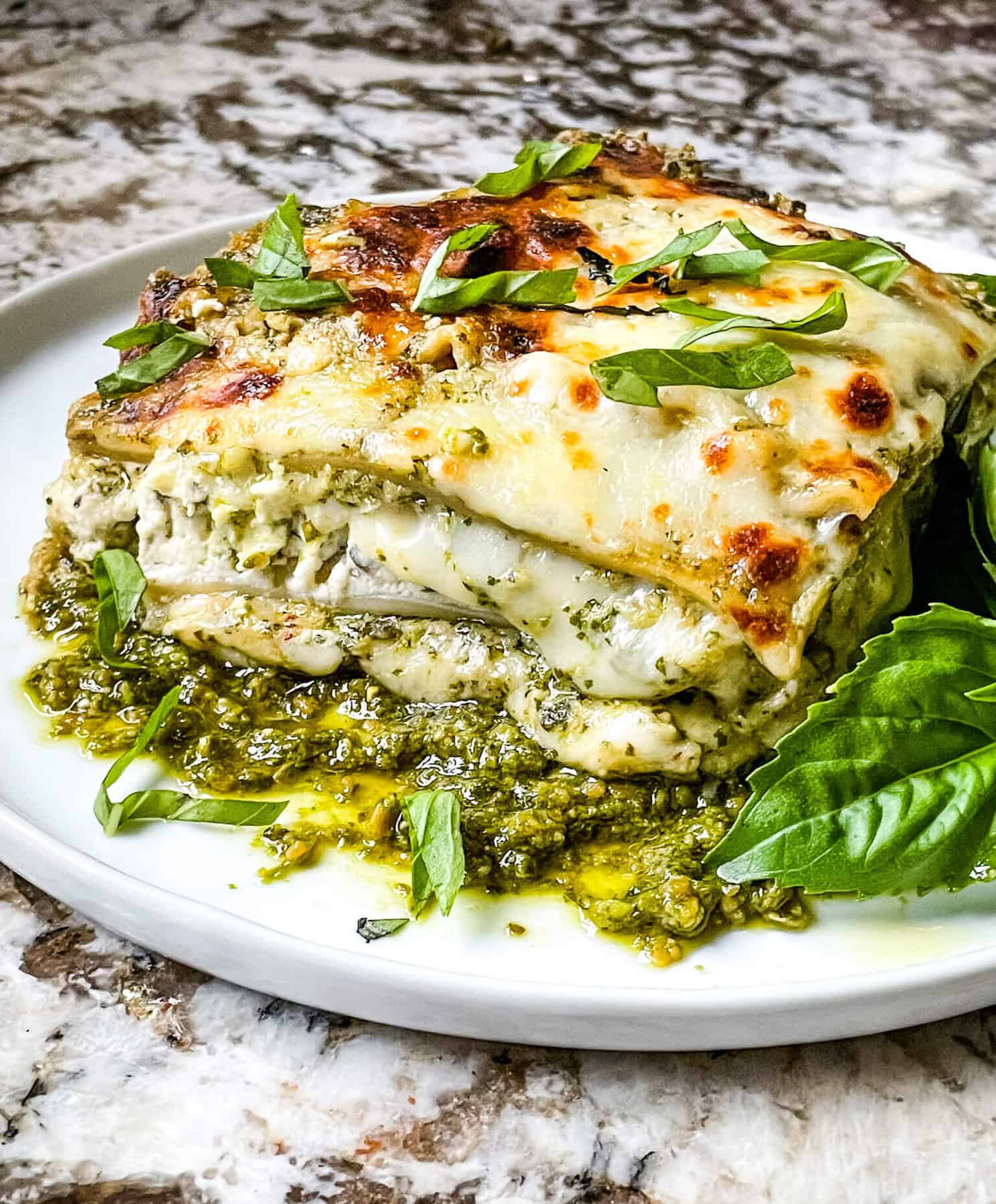 Side view of Lasagna al Pesto on a plate with dresh basil