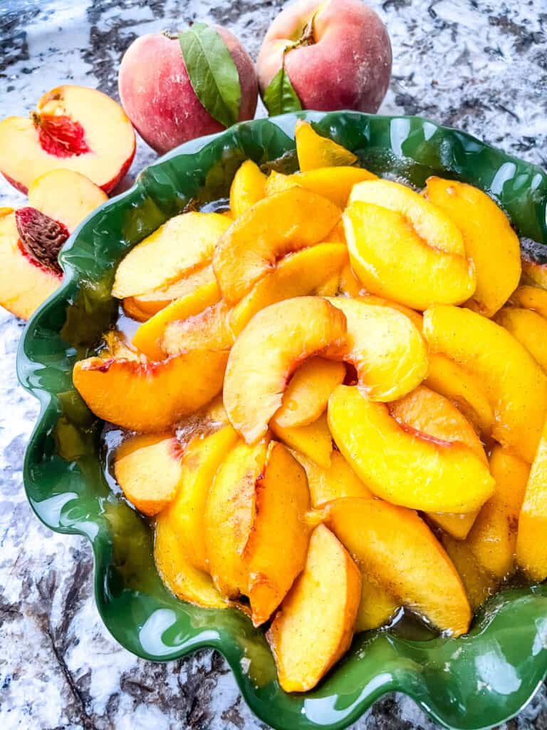 A green pie dish filled with the peach mixture