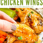Pin image of a hand holding a Honey Garlic Chicken Wing with title at top