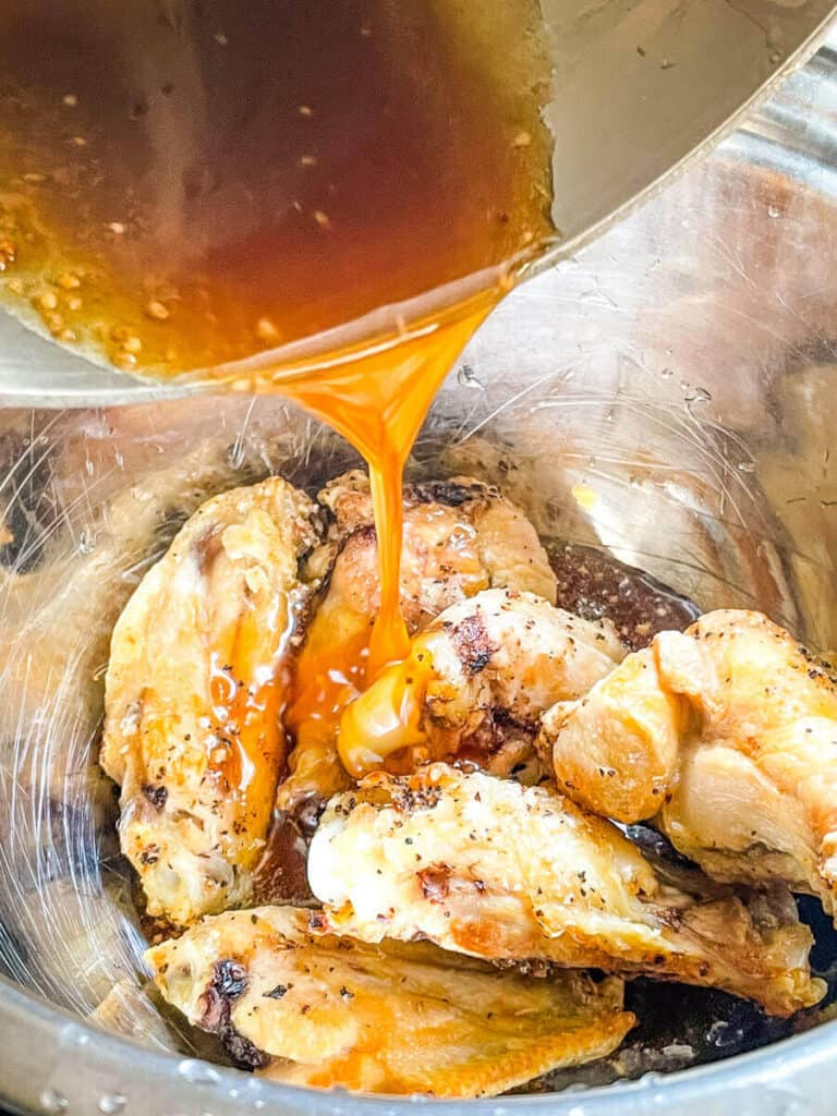 The sauce being poured onto the chicken in a bowl