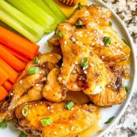 Top view of Honey Garlic Chicken Wings in a pile on a plate with carrots and celery