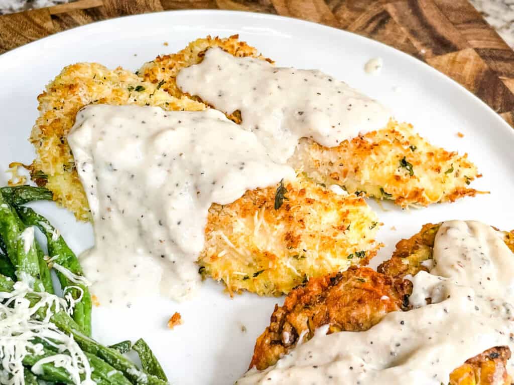 Parmesan Air Fried Chicken Tenders with White Gravy on top on a white plate