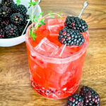 Blackberry Bourbon Sidecar in a glass with berries and thyme
