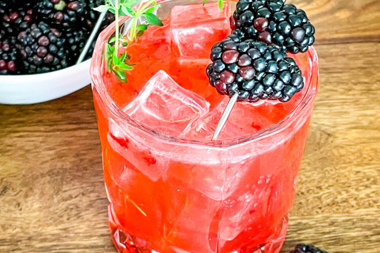 Blackberry Bourbon Sidecar in a glass with berries and thyme