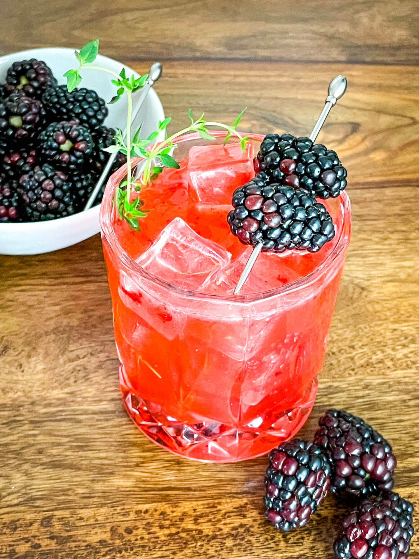 Blackberry Bourbon Sidecar in a glass with berries and thyme