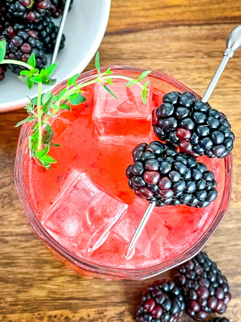 Top view of Blackberry Bourbon Sidecar with berries and thyme garnishes