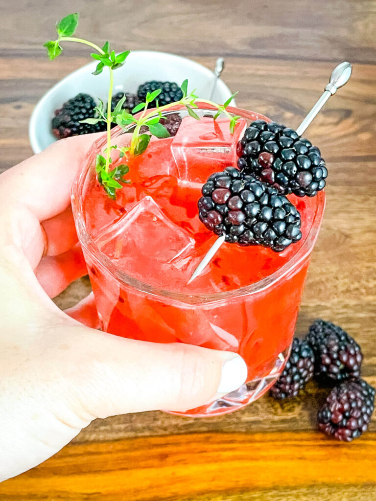 A hand holding a Blackberry Bourbon Sidecar