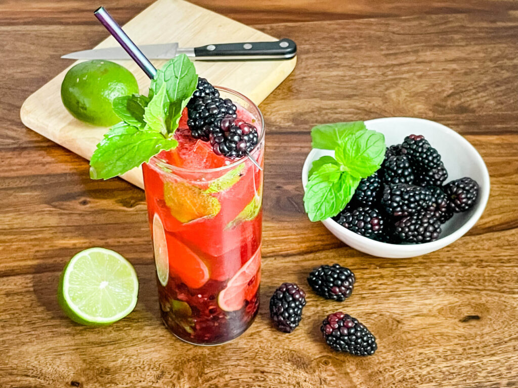 The drink on a table with berries and a cutting board around it