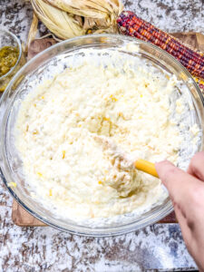 A hand mixing all of the ingredients together in a large bowl