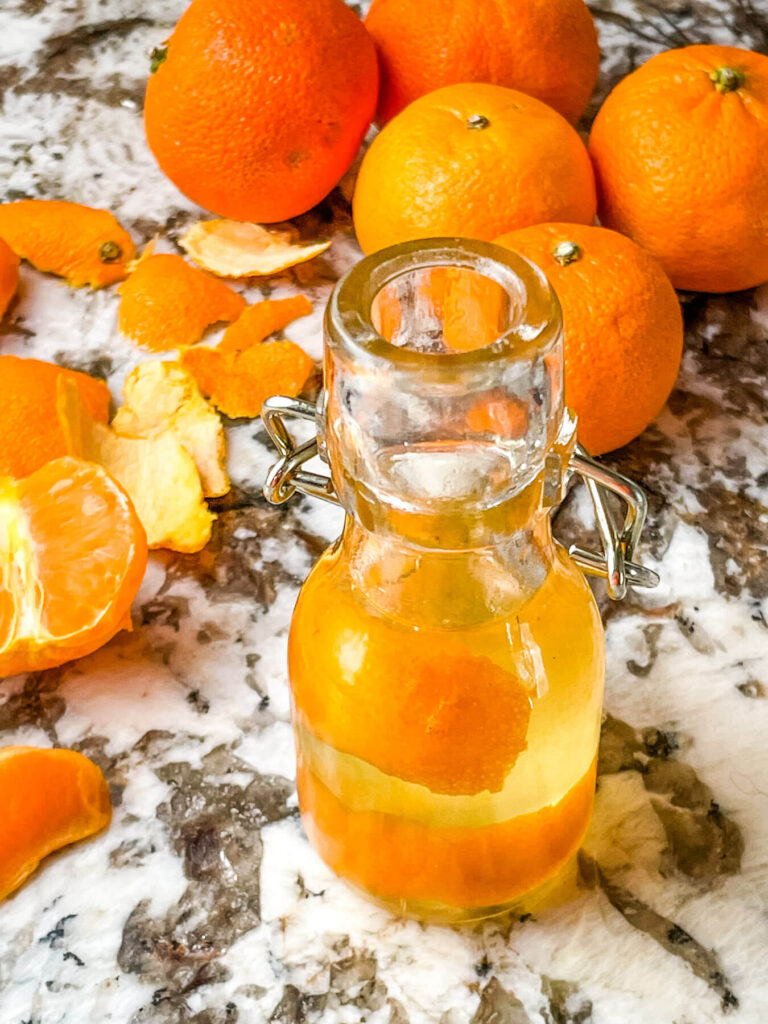 The liquid in a small bottle with fruit behind it