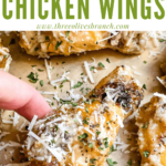 Pin of a hand grabbing a Parmesan Garlic Chicken Wing with title at top