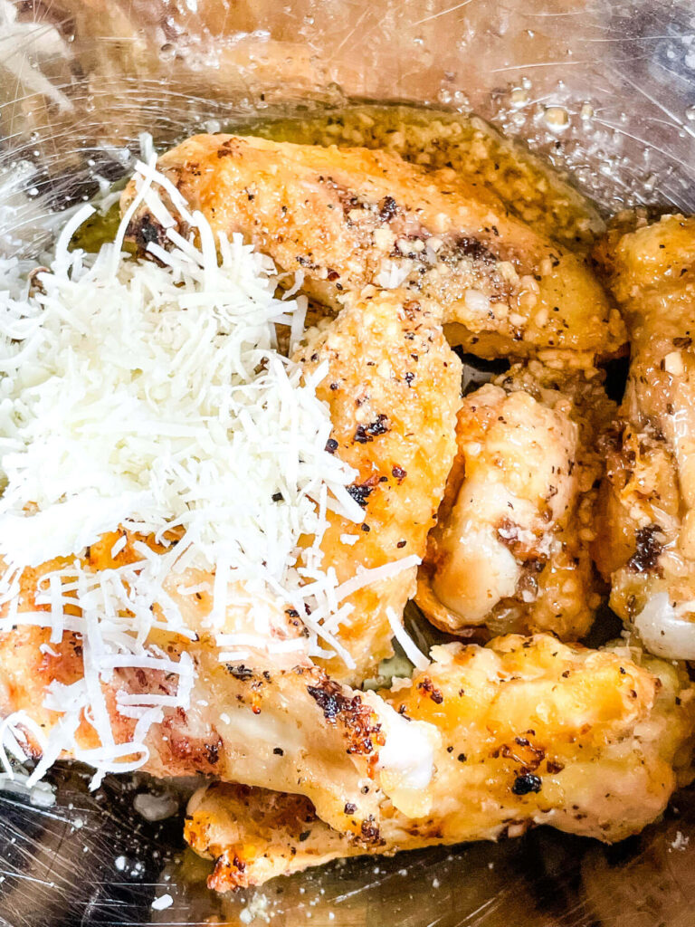The wings being tossed in a bowl with the toppings