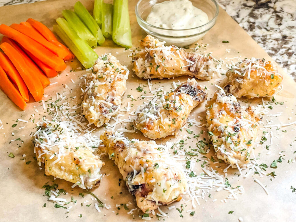 The wings being served on butcher paper with vegetables and dip