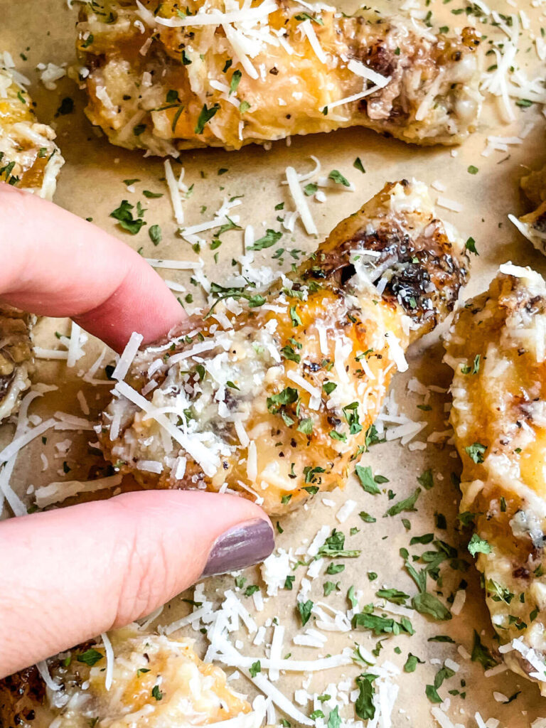 A hand grabbing a Parmesan Garlic Chicken Wing