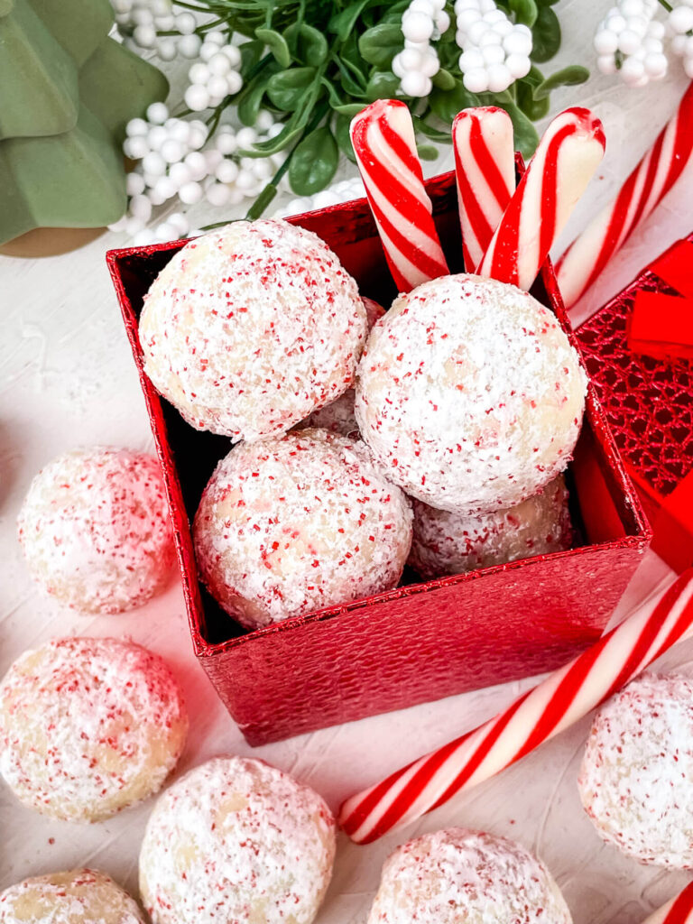 Peppermint Snowball Cookies in a red box with cookies around it