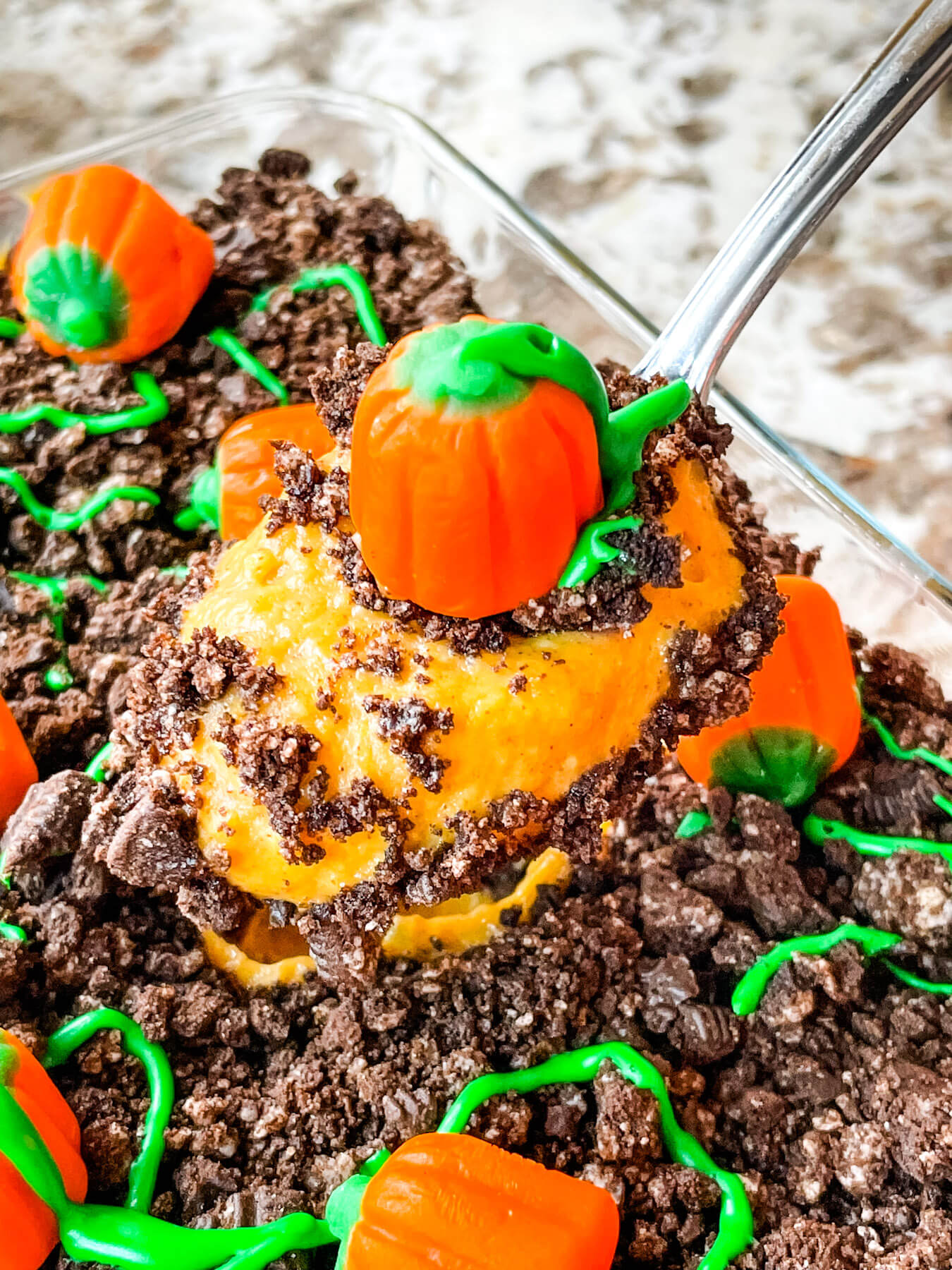 A spoon scooping some pudding out of the dish with a pumpkin on top