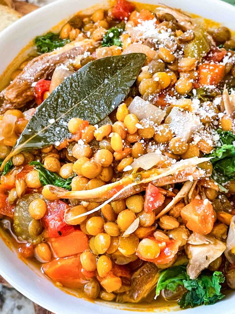 Close up of Turkey Lentil Soup with parmesan cheese and a bay leaf on top