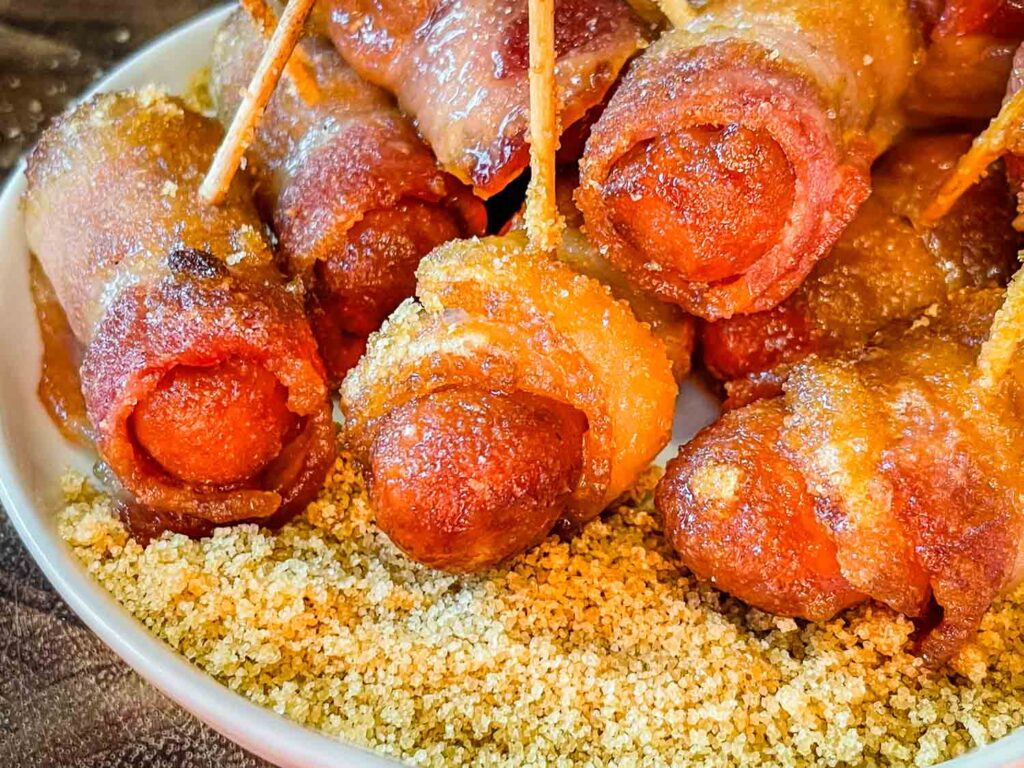 Cooked Bacon Wrapped Smokies in a pile on top of sugar mustard mixture