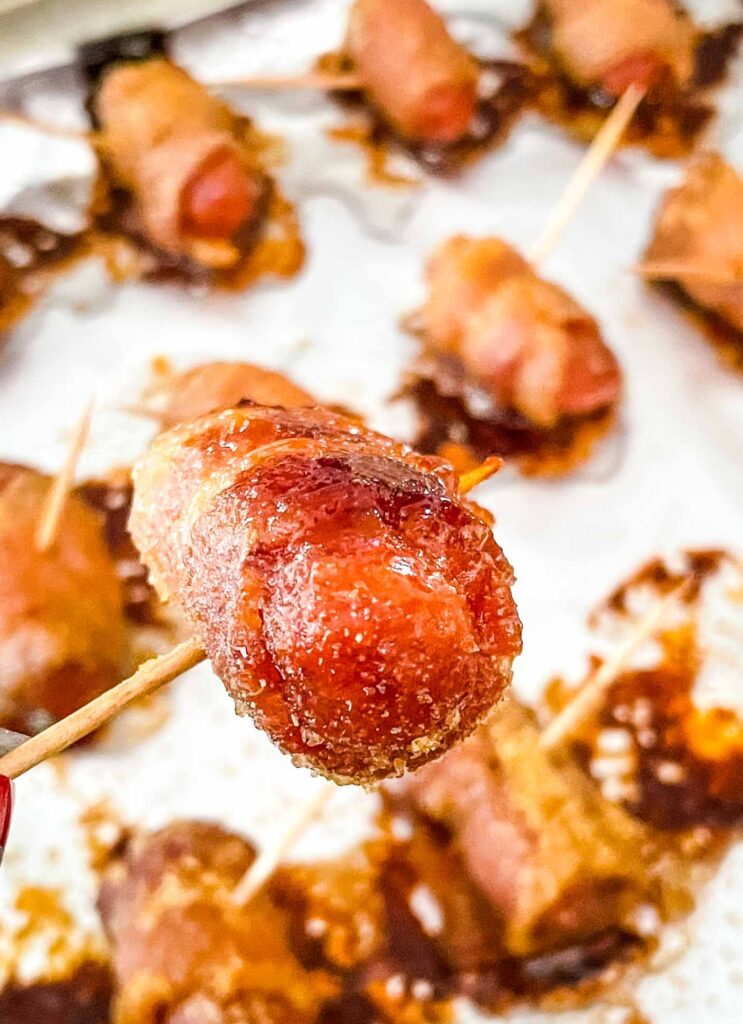 A close up of one smokie after being cooked held above the baking sheet